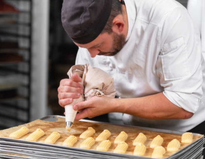 Pâtissier en train de dresser une pâte à l'aide d'une poche à douille 